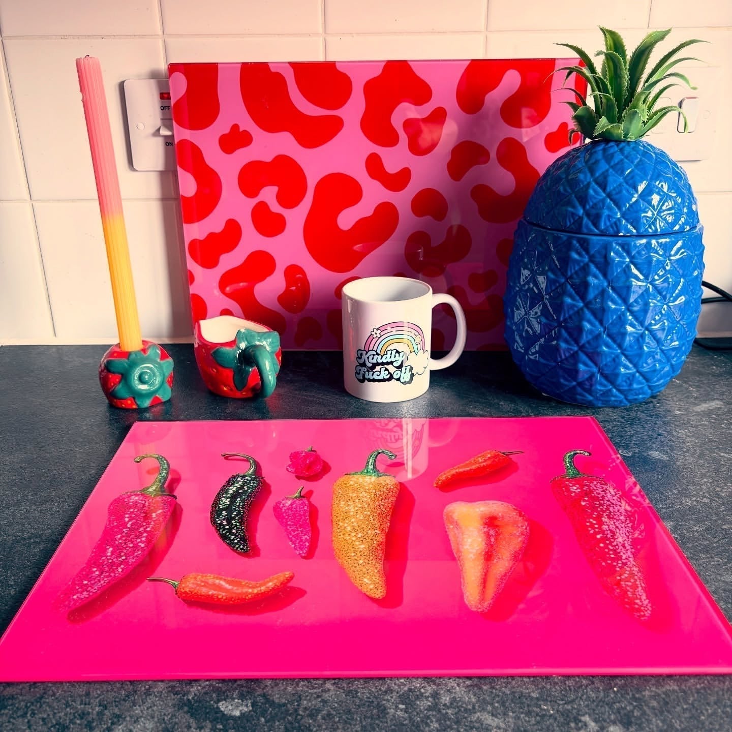 A colourful pink Chilli glitter pepper glass chopping board on a kitchen counter - handmade in the U.K.