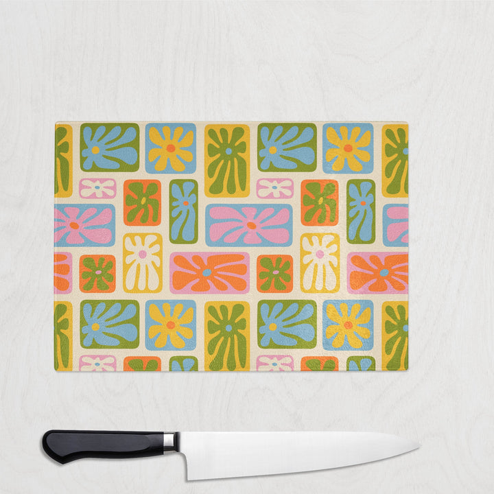 Glass chopping board with bold retro 70s floral pattern in pink, orange, green, yellow and blue