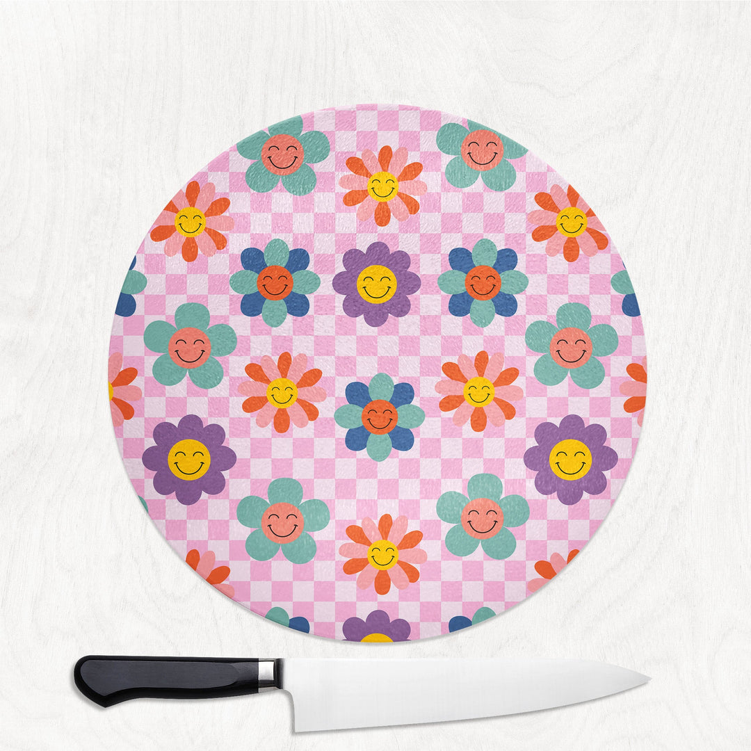 Round pink cutting board with colorful flower pattern on a white background