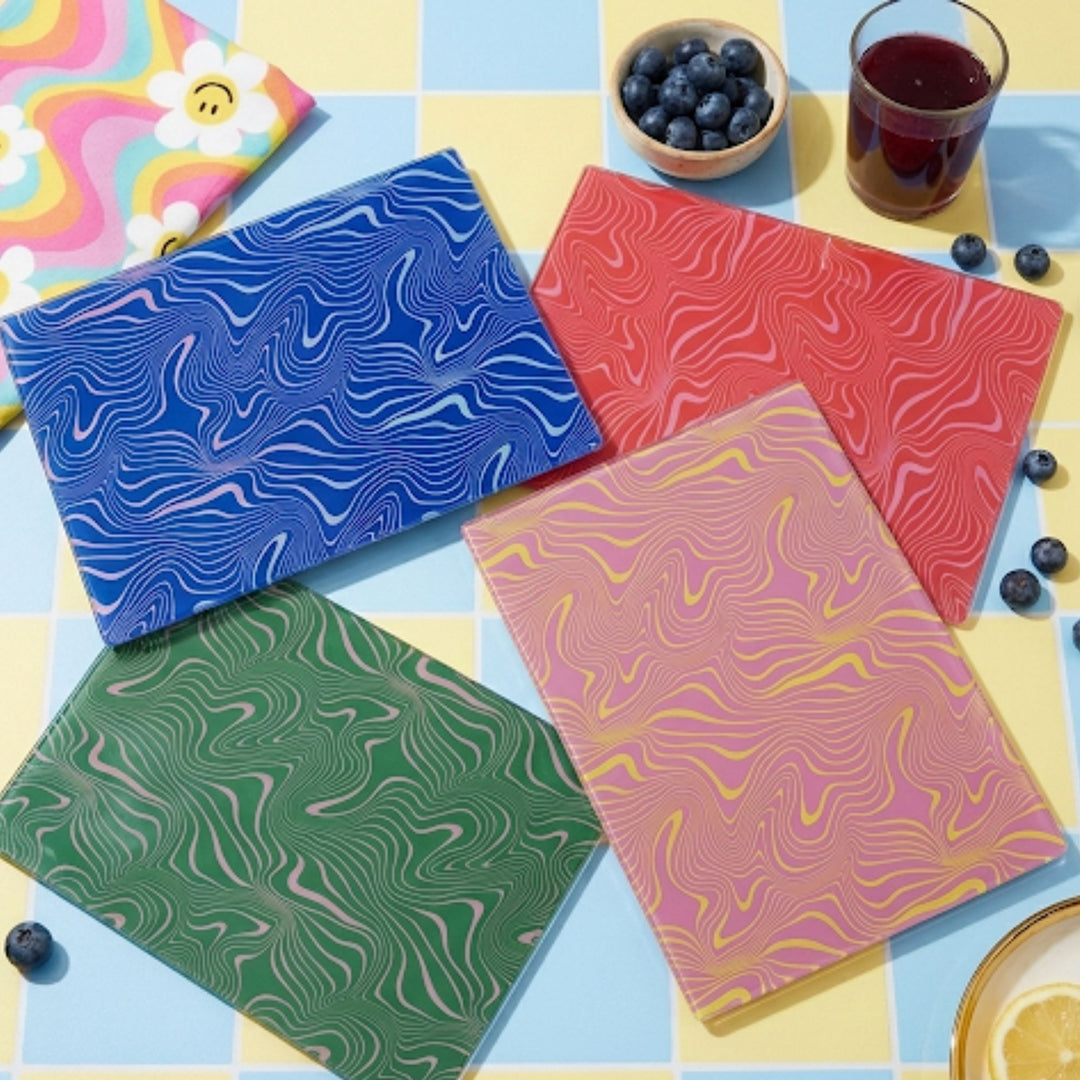 Four colorful notebooks with marbled patterns on a multicolored surface.
