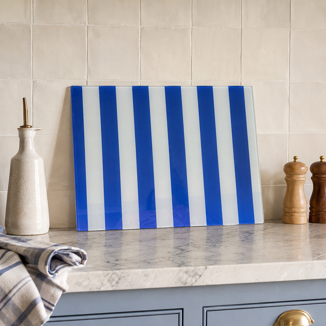 Blue and white striped glass worktop saver on a kitchen countertop with tiled wall in the background.