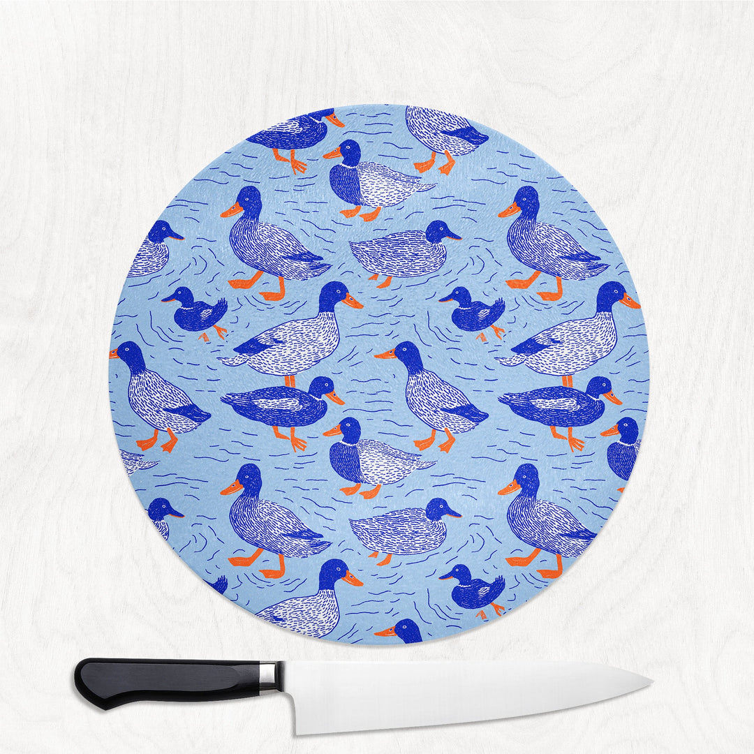 Blue Ducks round glass chopping board with hand-illustrated mallards on blue water