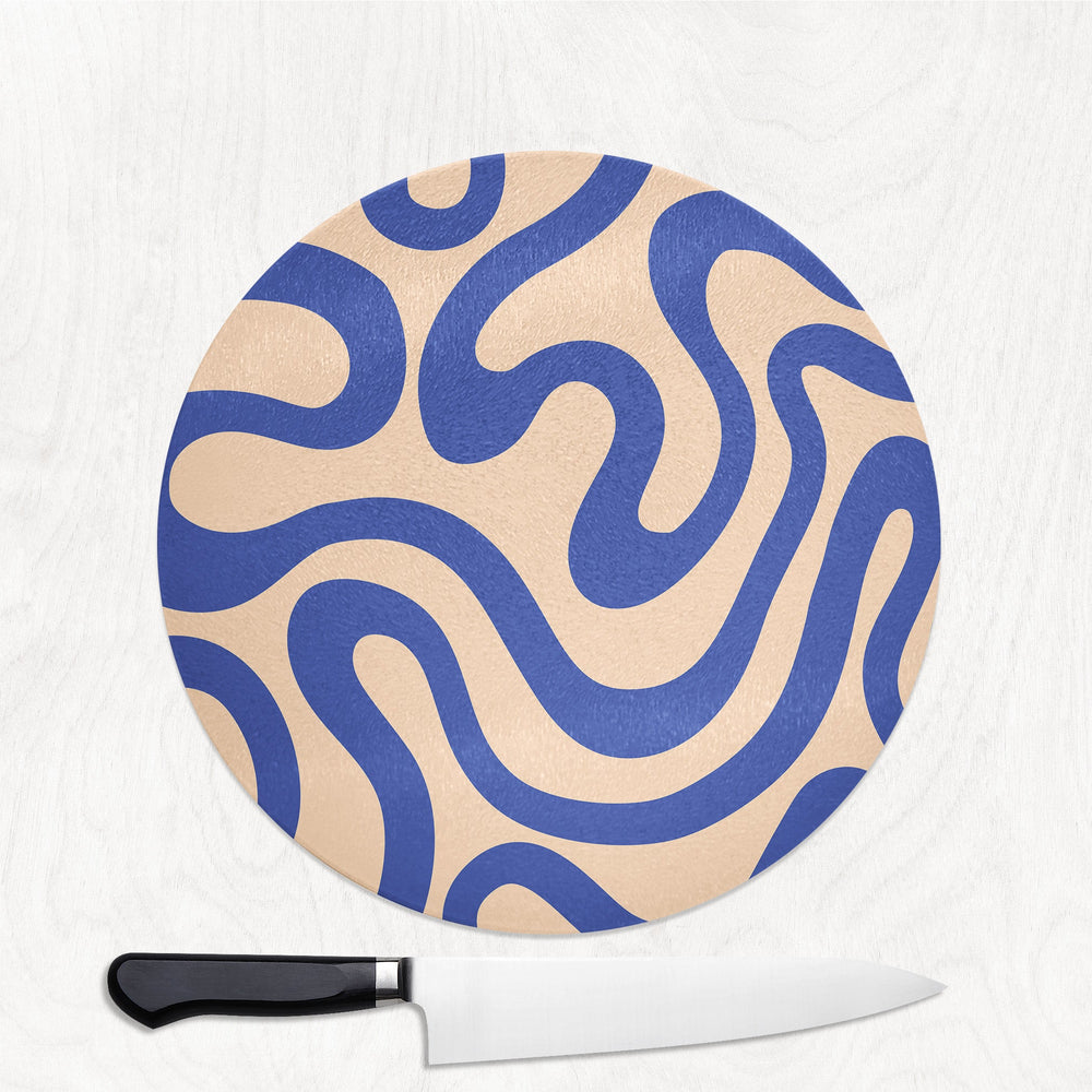 Round cutting board with blue and beige pattern and a knife on a white background