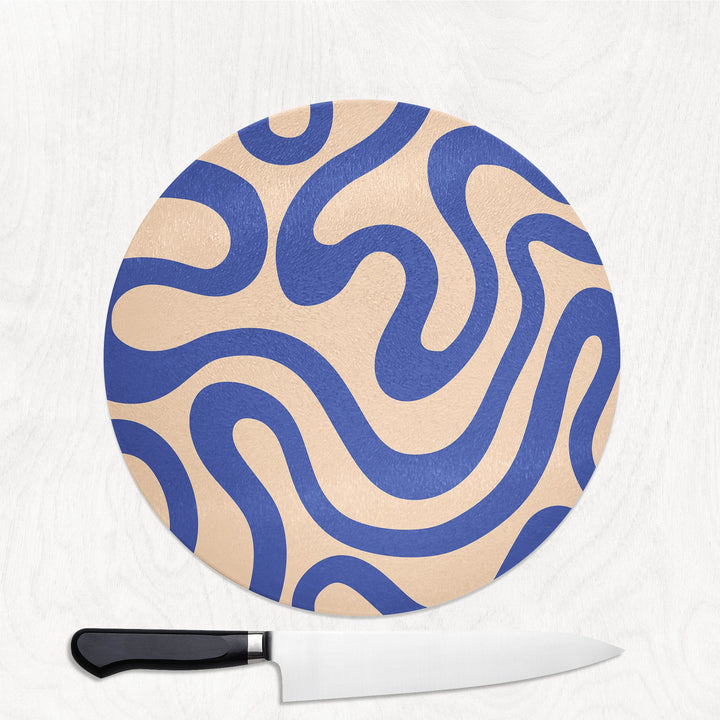 Round cutting board with blue and beige pattern and a knife on a white background