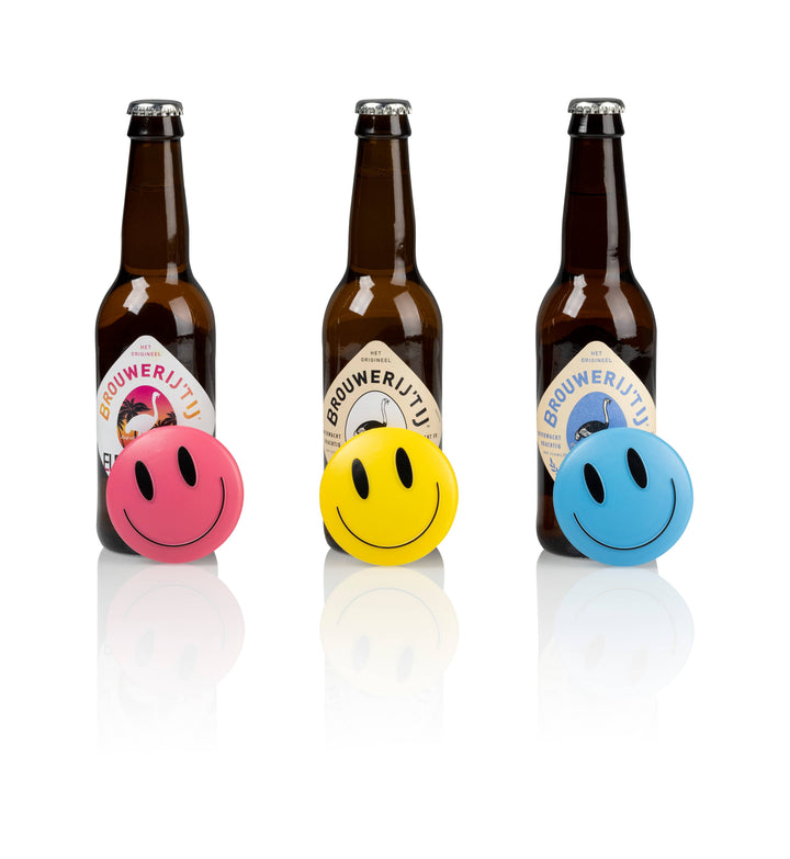 Three bottles of Brouwerij Utz with smiley face balls in pink, yellow, and blue on a white background.