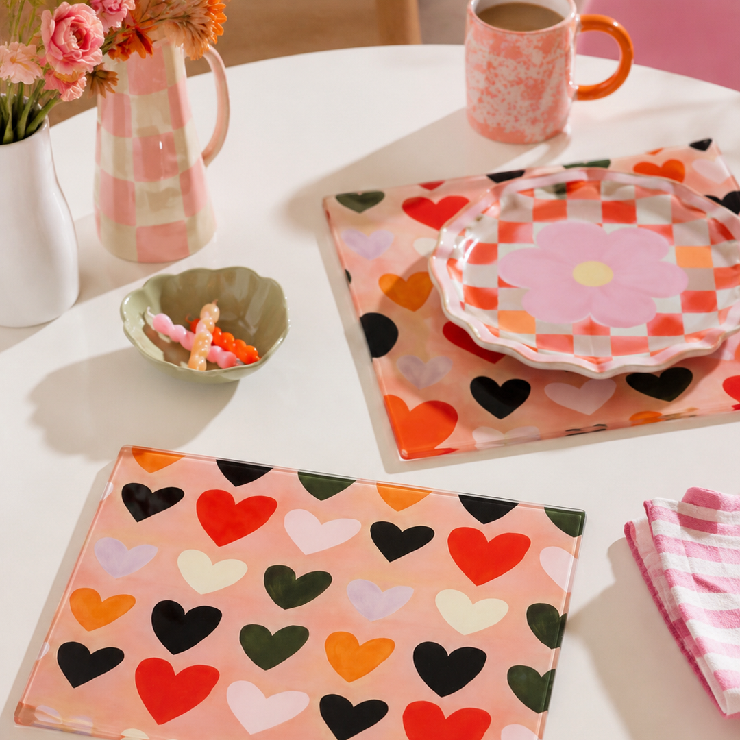 Table setting with boho heart-patterned glass placemats and napkins on a white table.