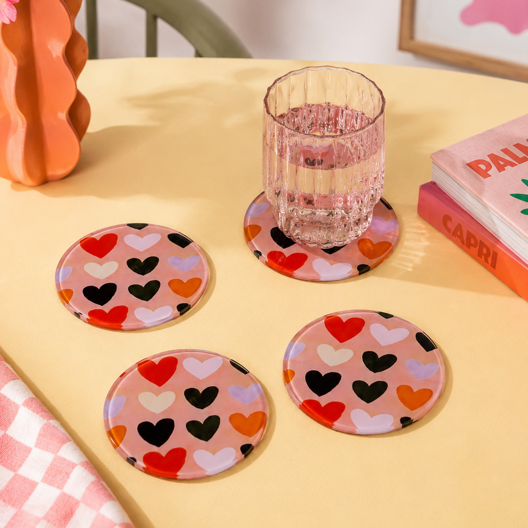 Heart-patterned coasters on a table with a glass of water and a vase of flowers. Dopamine Decor 