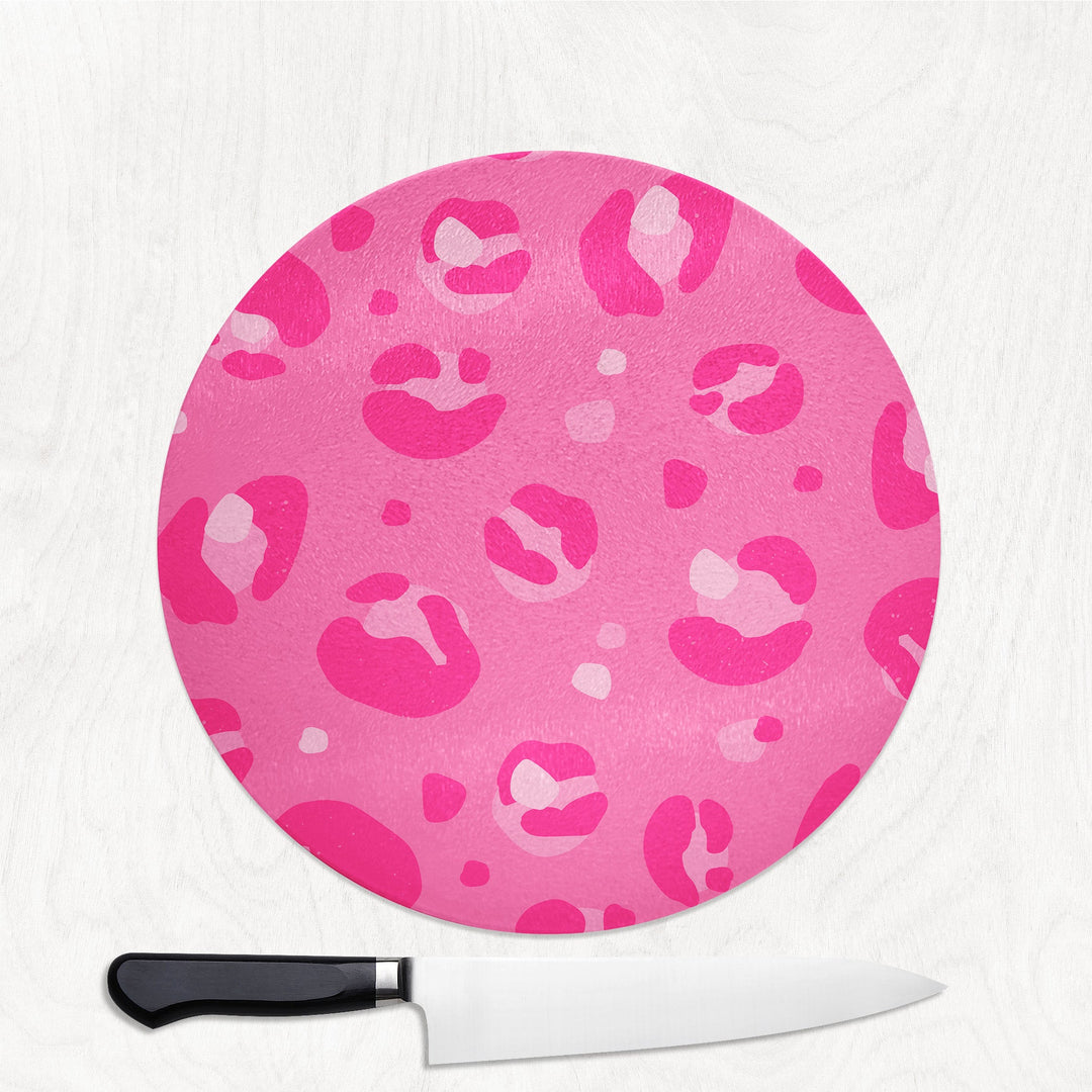 Pink leopard print cutting board with a knife on a white background