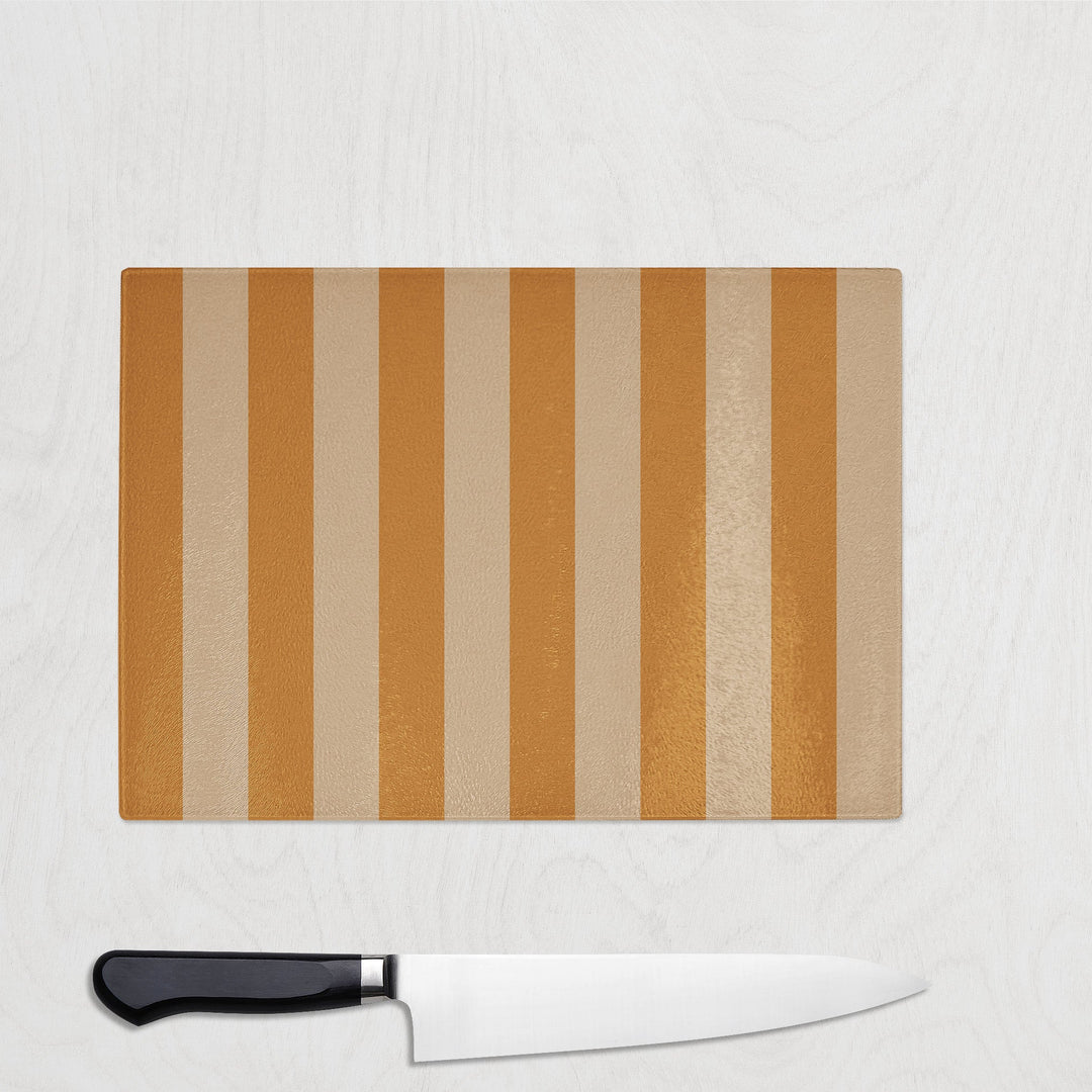 Striped mustard cutting board with a knife on a light gray background