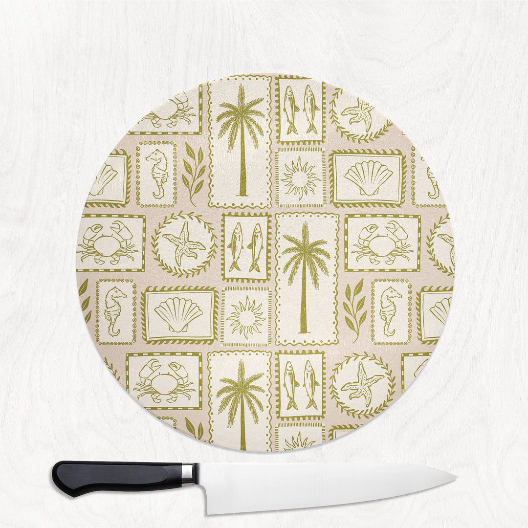 Coastal Chic round glass chopping board with vintage stamps of palms, shells, seahorses and starfish