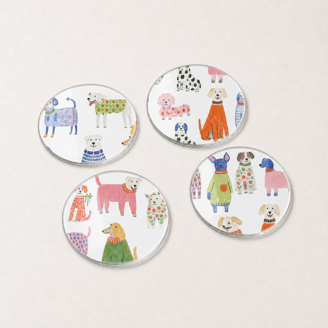 Set of four round glass coasters with colorful dog illustrations on a light gray background