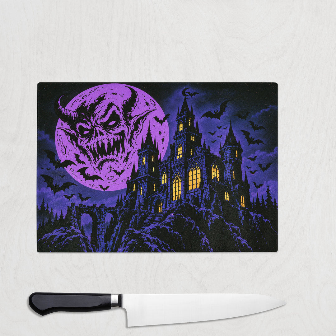 Comic Haunted House glass chopping board with a lit gothic castle, bats and a snarling face in a violet sky