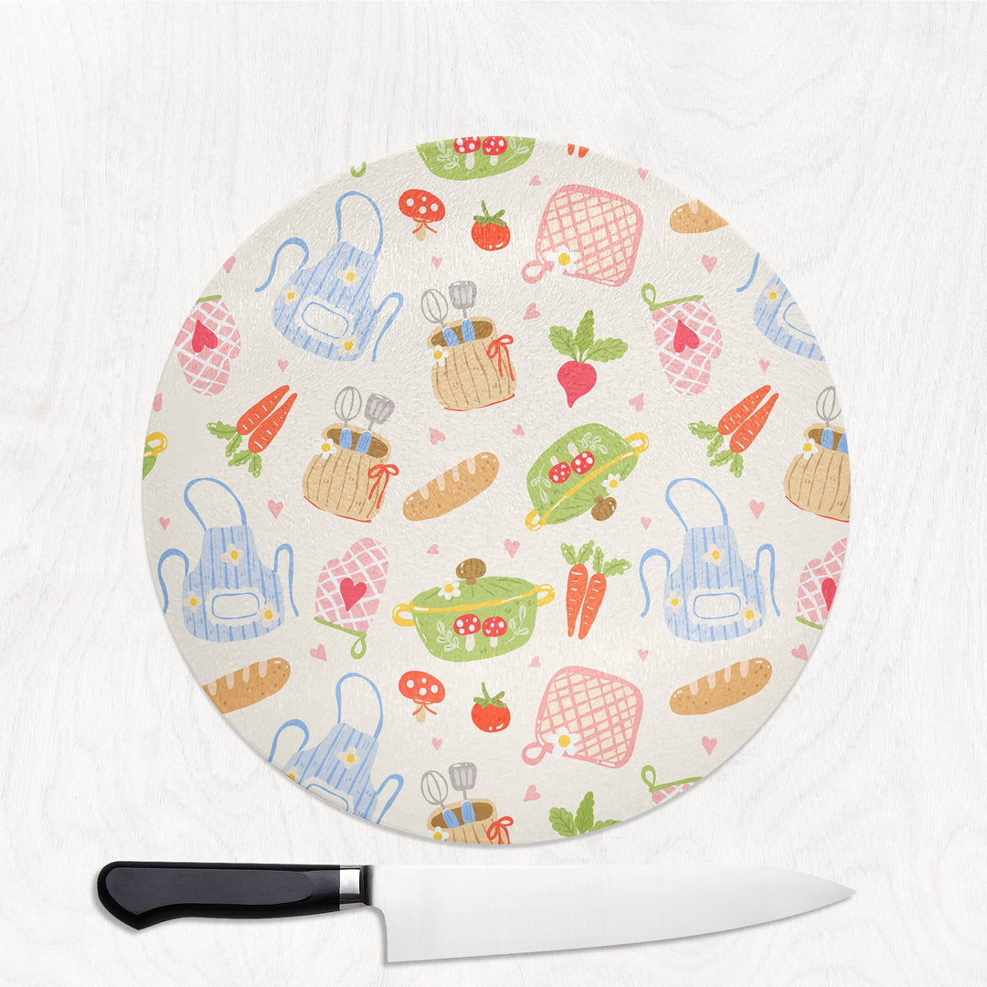 Country Kitchen round glass chopping board with aprons, pots, bread and kitchen veg