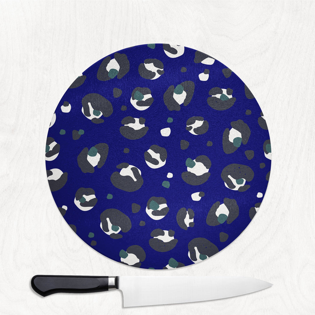 Round blue cutting board with leopard print animal pattern and a knife on a white background