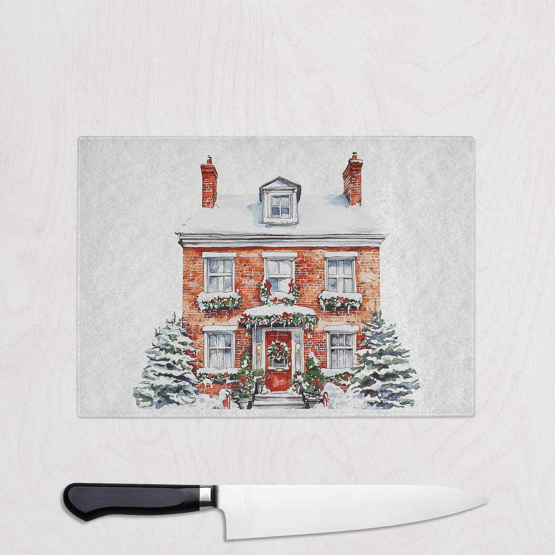 Christmas-themed cutting board with a house illustration on a white surface with a knife.