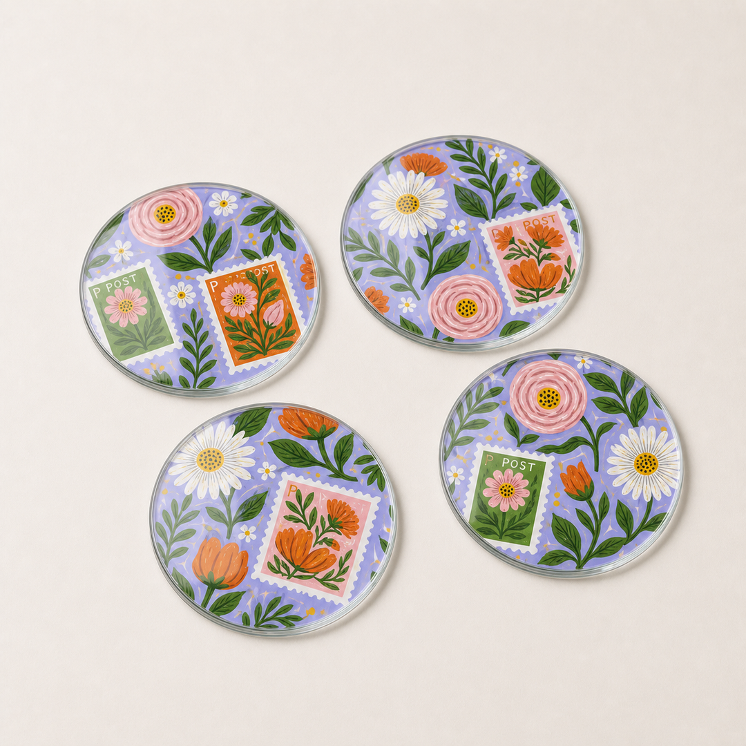 Set of four glass round coasters with floral and stamp design on a light beige background