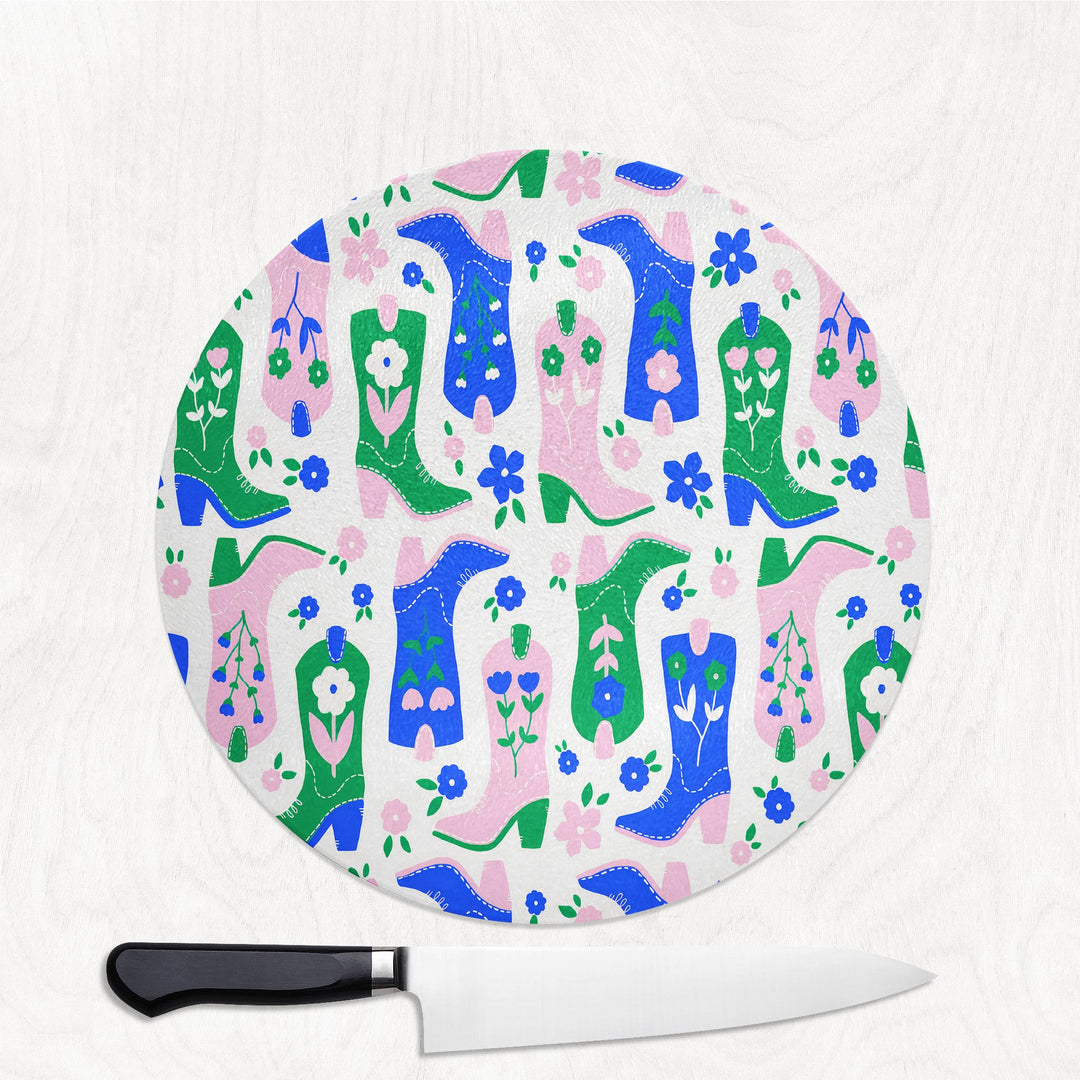 Round cutting board with colorful cowboy boot pattern on a white background