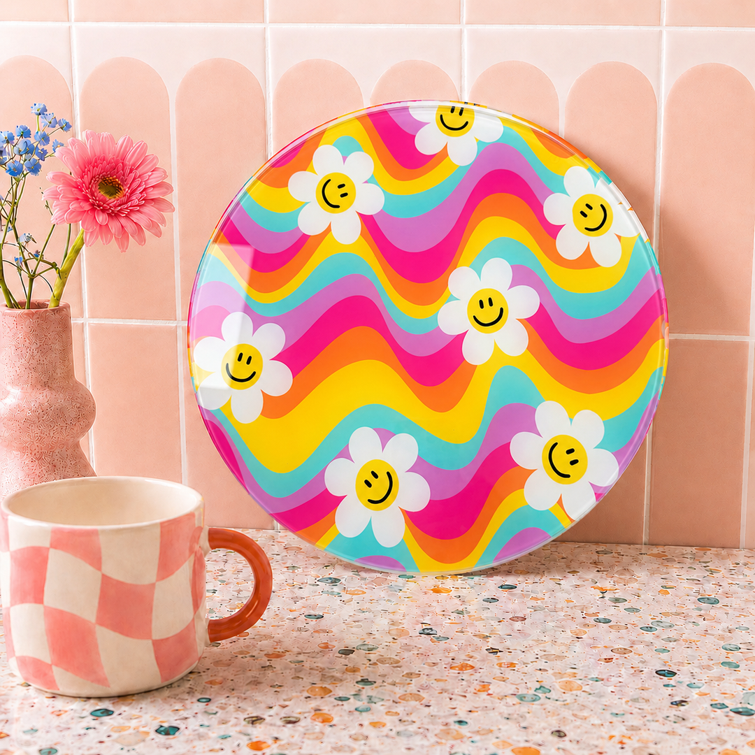 Colourful plate with smiley face flowers next to a mug on a speckled countertop.