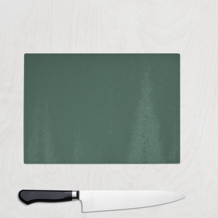 Green cutting board with a knife on a light gray background