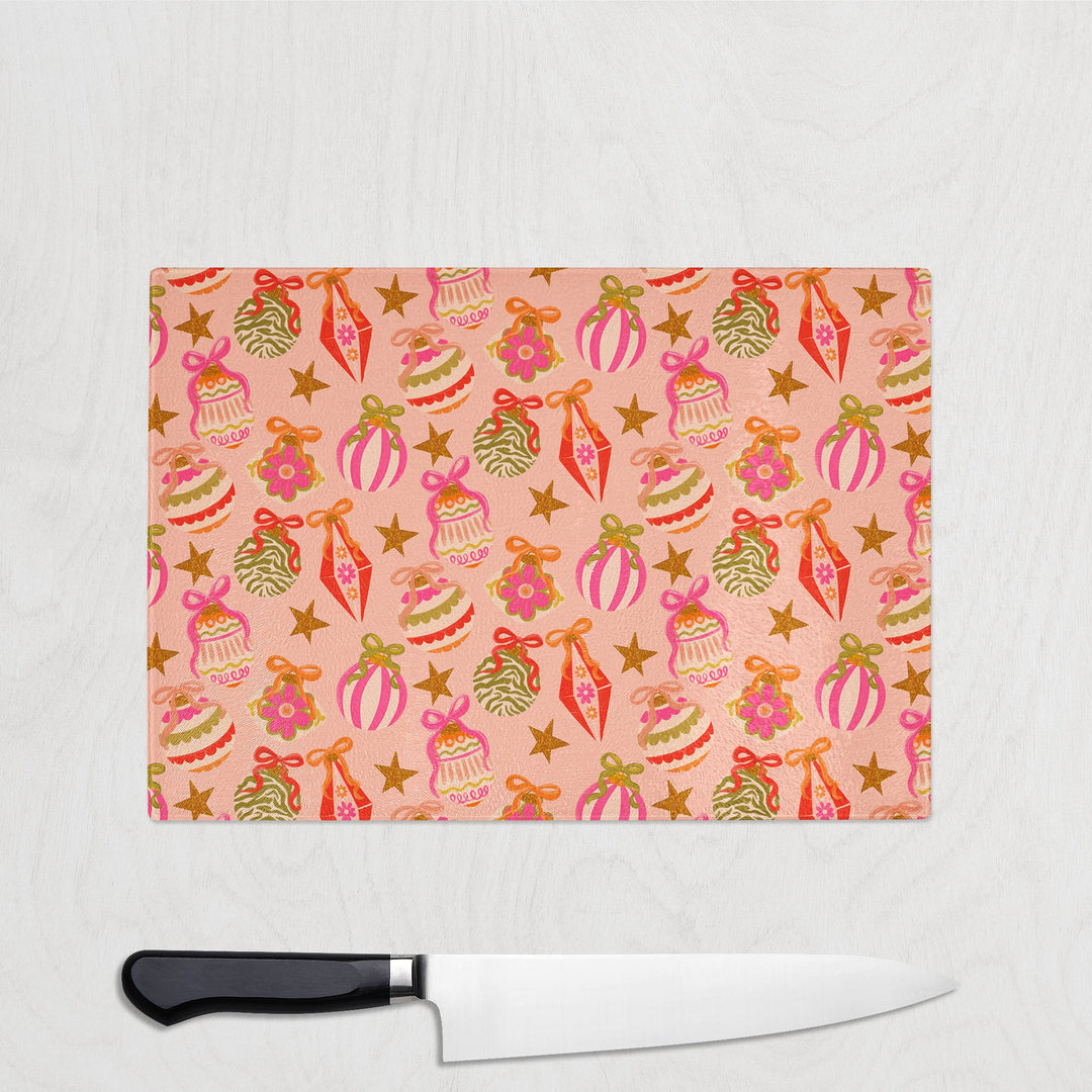 Glass cutting board with festive bauble design and a knife on a light gray background