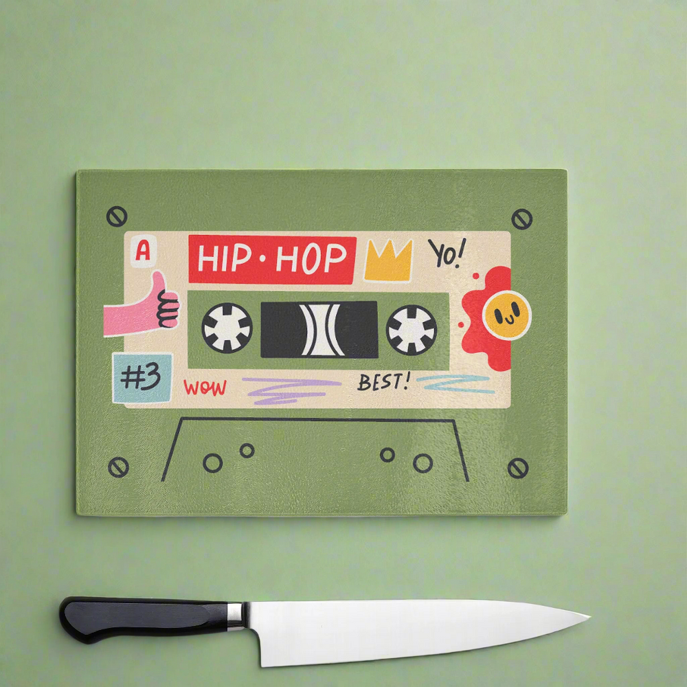 The Yililo Green Hip Hop Cassette Tape Chopping Board features a colorful retro design, shown on a green surface with a kitchen knife—ideal kitchenware for music lovers and a fun gift for home cooks.