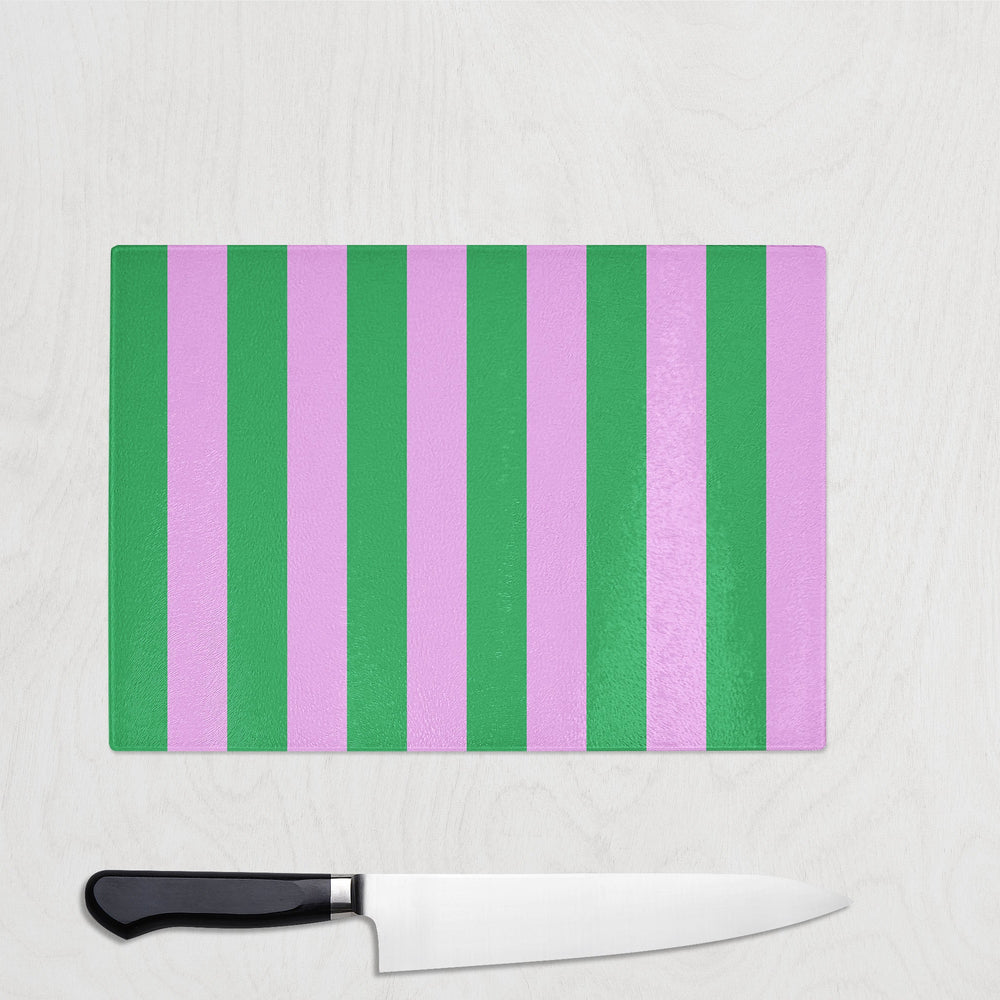 Striped green and pnk cutting board with a knife on a light gray background