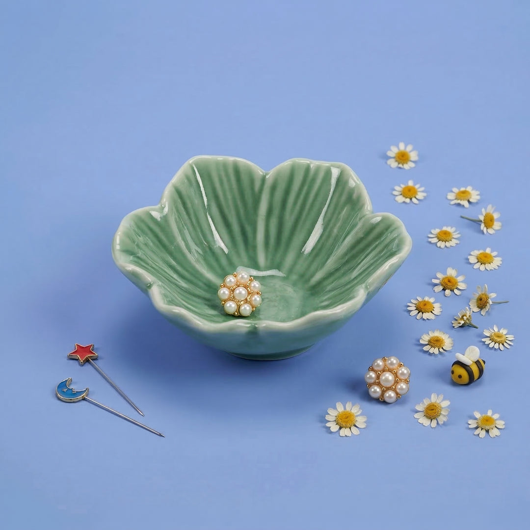 Green ceramic bowl with decorative items on a blue background