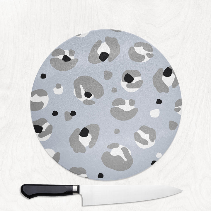 Round cutting board with gray leopard print pattern on a white background