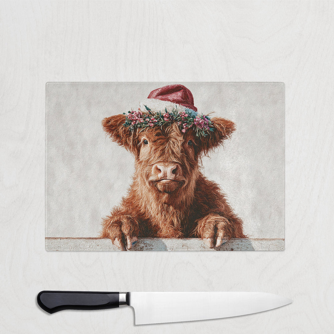 Cute cow wearing a Santa hat with a floral wreath on a light gray background, next to a knife.