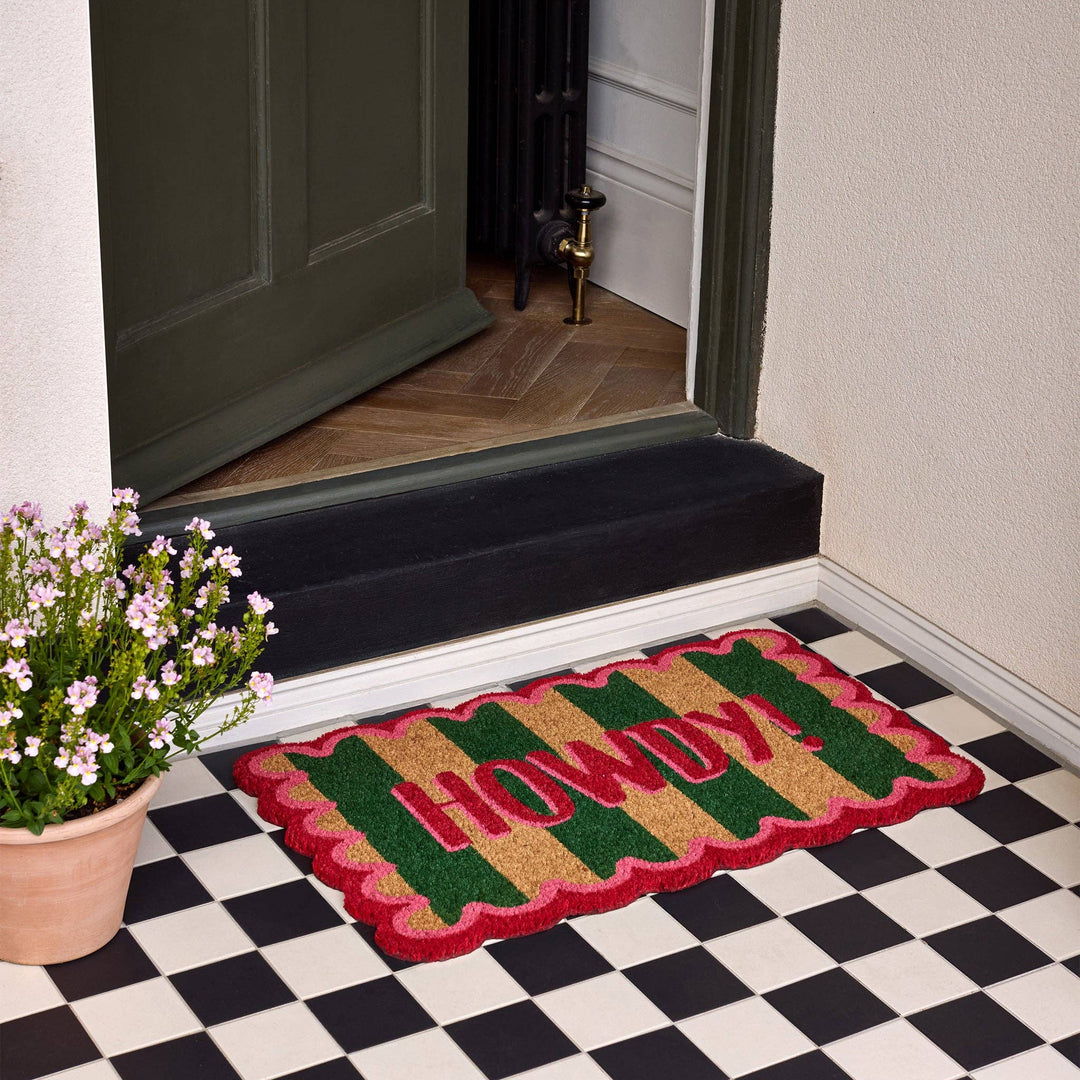 Decorative doormat with 'Welcome' text on a checkered floor in front of a door.
