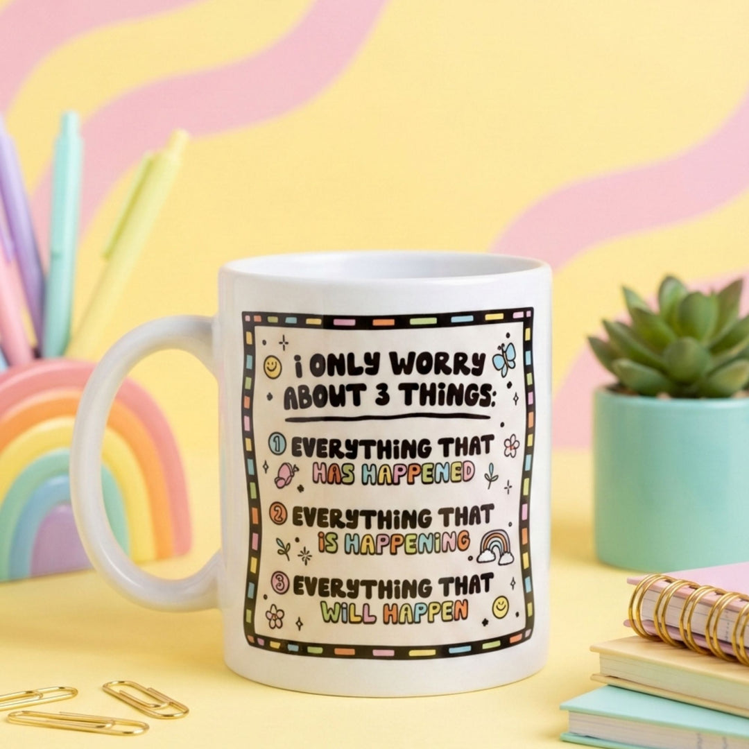 White mug with humorous text I Only Worry About Three Things
design on a colorful background