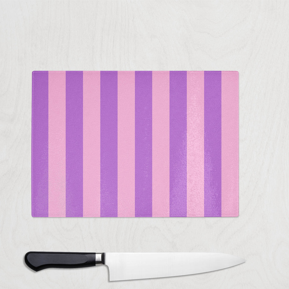 Purple and pink striped cutting board with a knife on a white surface