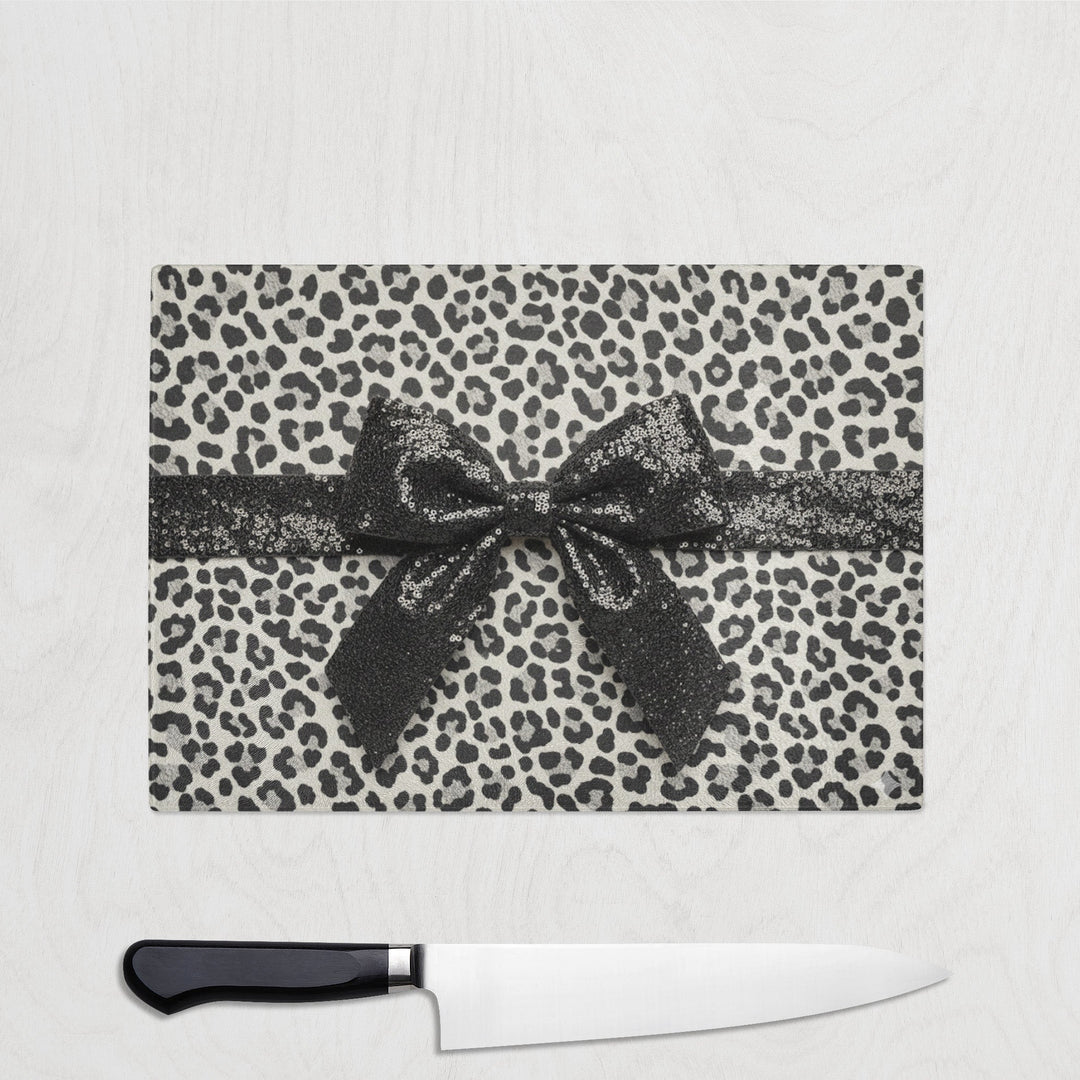 Leopard print cutting board with a bow and a knife on a white background