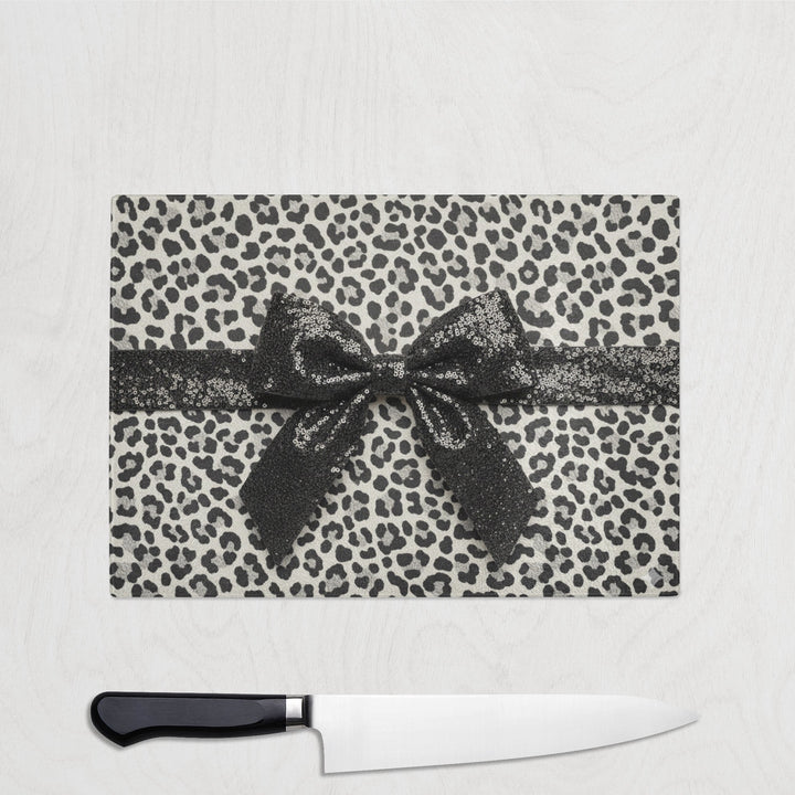 Leopard print cutting board with a bow and a knife on a white background