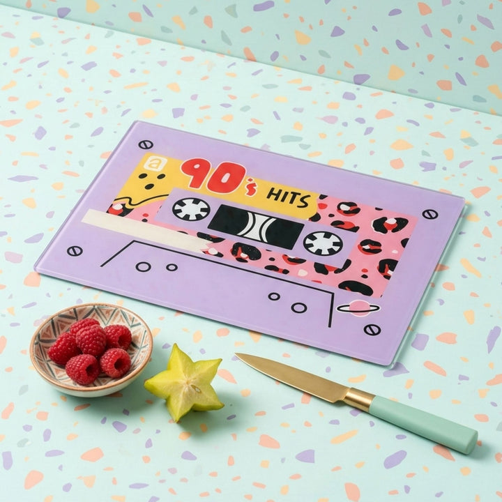 Cassette tape-themed glass chopping board and with '90s Hits' text on a colourful patterned surface.
