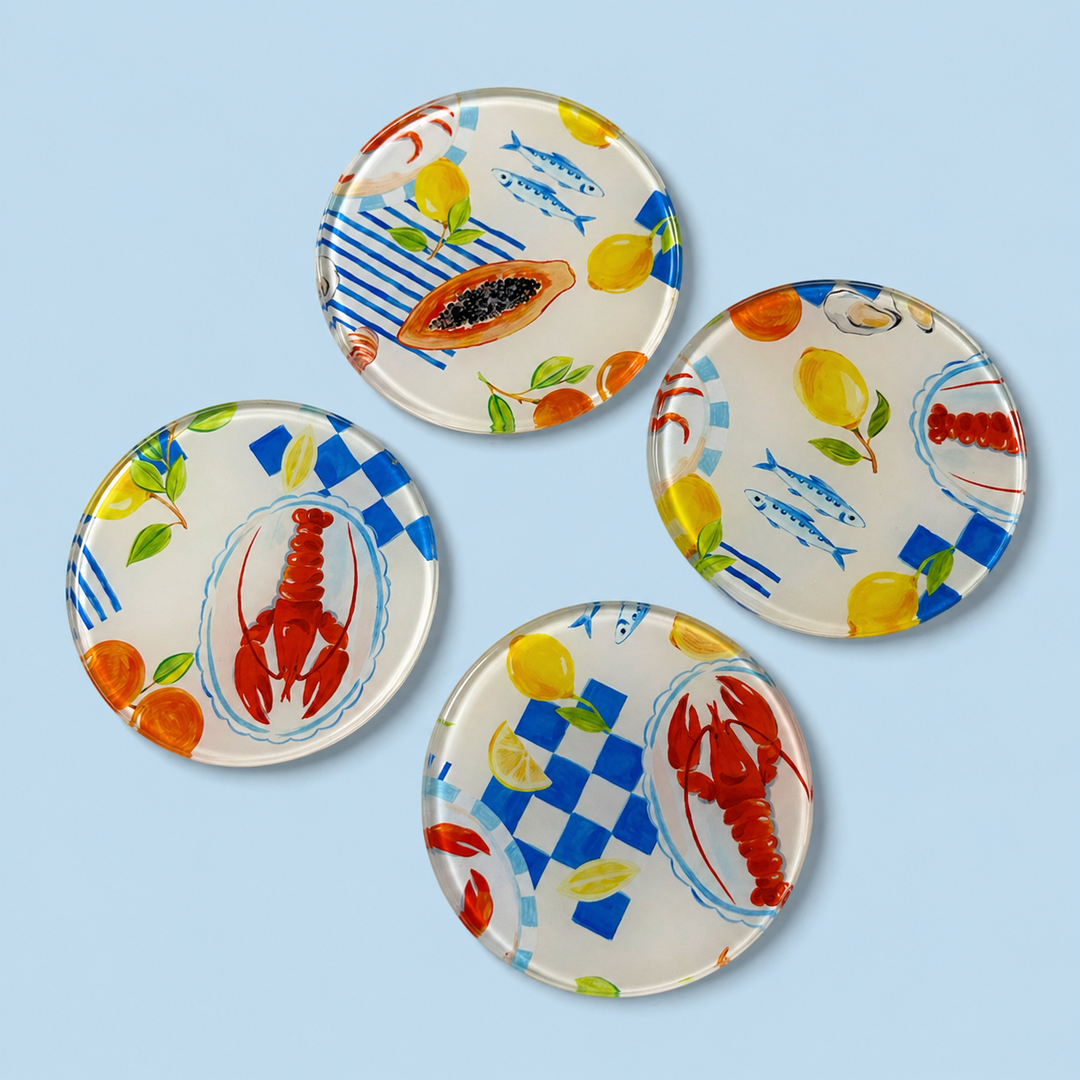 Set of four decorative glass coasters with lobster, lemon, and checkered patterns on a light blue background.