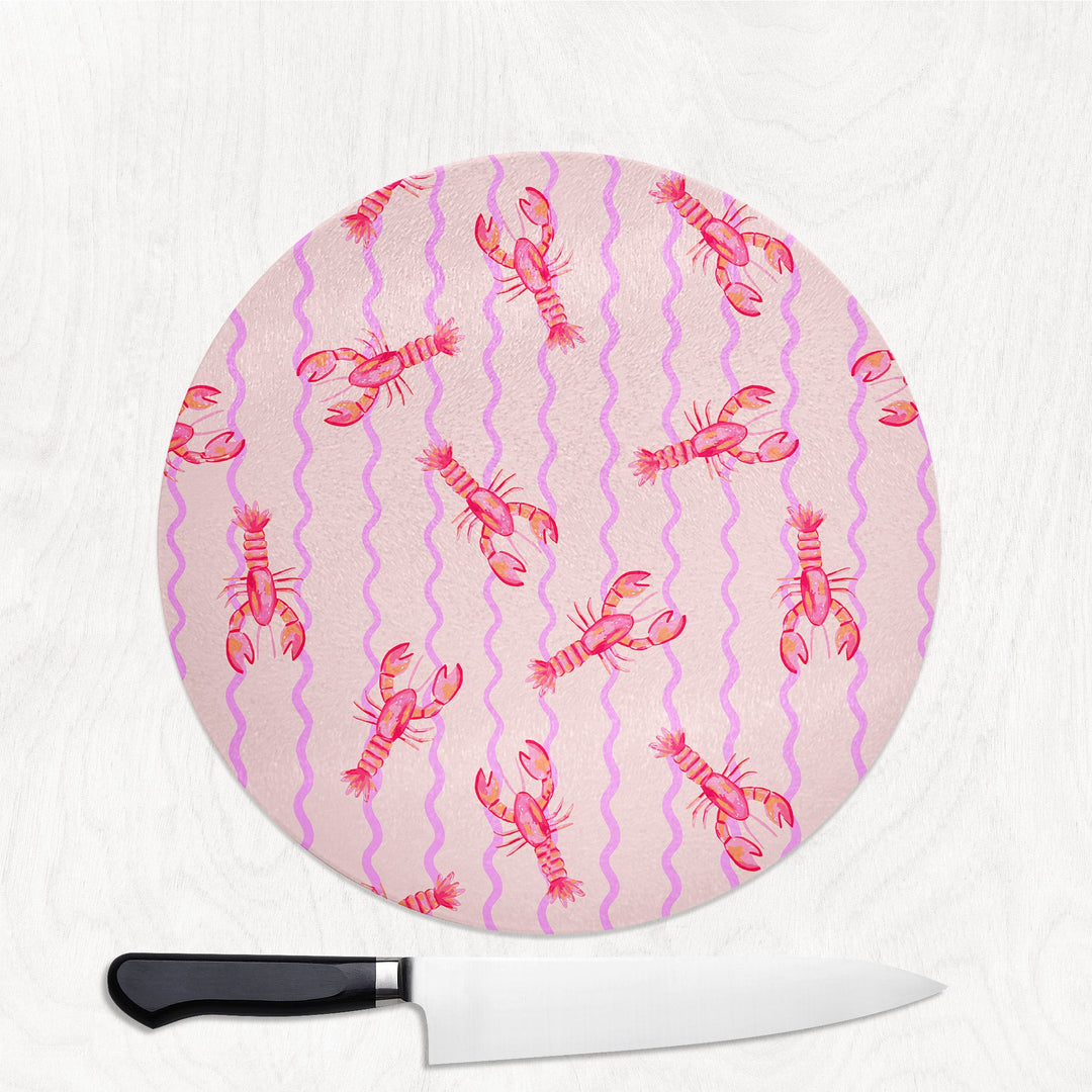 Round cutting board with pink lobster pattern on a white background