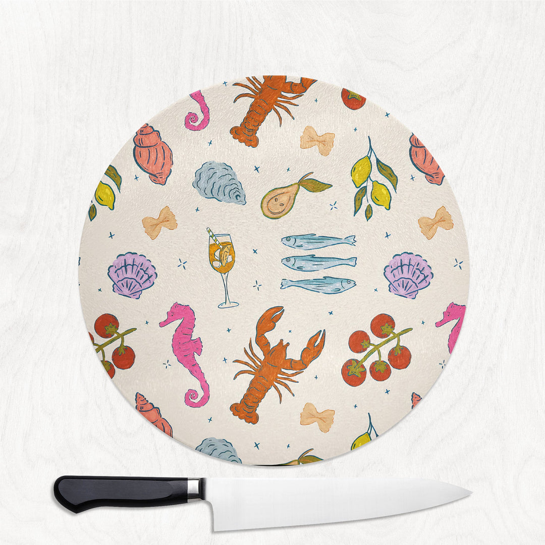 Round cutting board with colorful sea-themed design and a knife on a white background