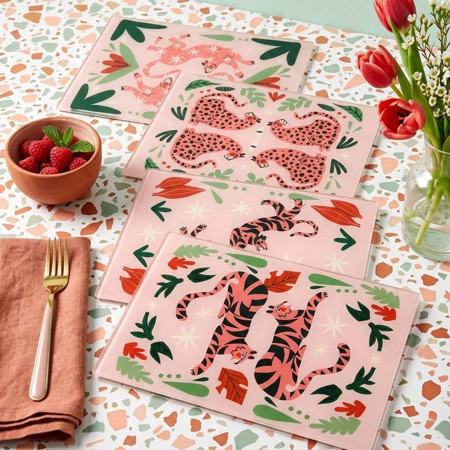 Set of glass placemats with animal prints on a patterned tablecloth.