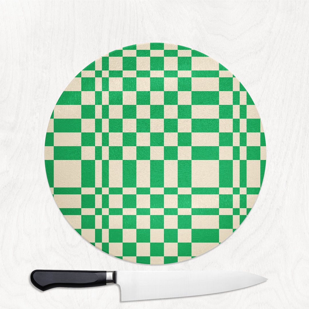Round green and white checkered cutting board with a knife on a white background