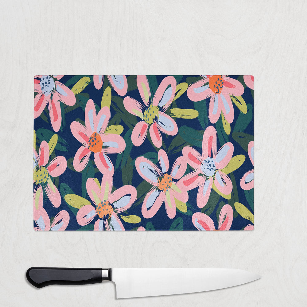The Yililo Midnight Bloom Glass Chopping Board features pink, white, and green flowers on a dark blue background—an elegant way to add a nature-inspired touch to your kitchen. Includes space for your knife on light surfaces.