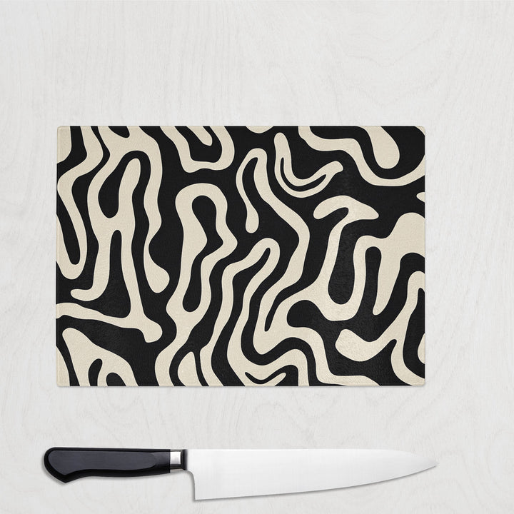 Glass chopping board with abstract black and cream swirling pattern – Midnight Melt design