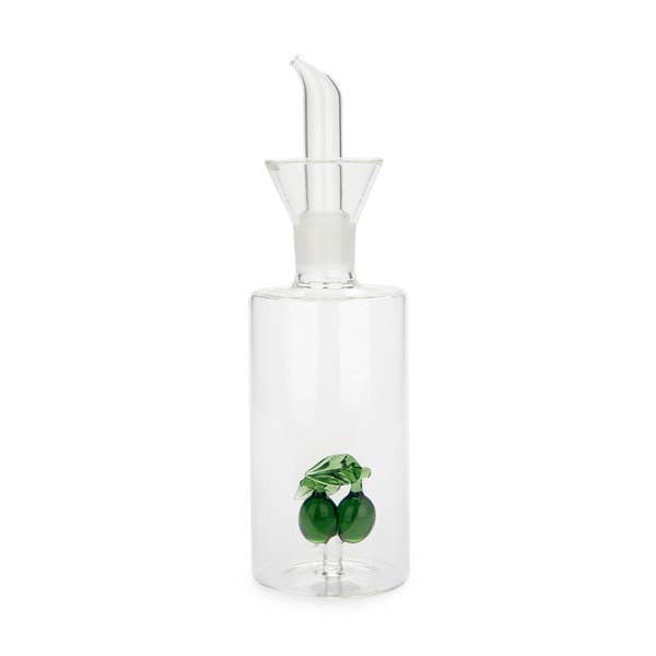 Clear glass oil dispenser with a white pump and green olives on a white background