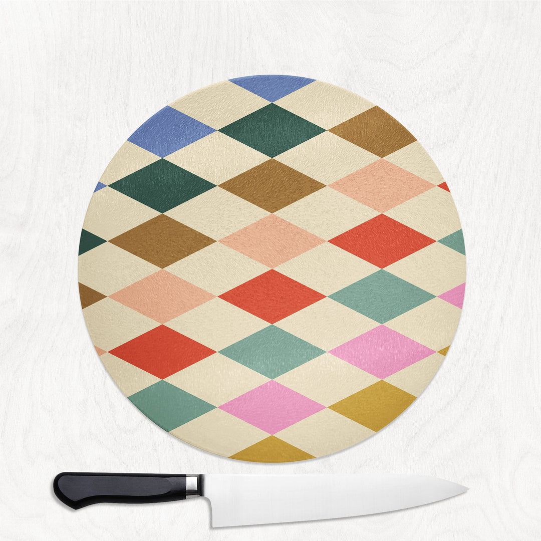 Round cutting board with a colorful geometric pattern and a knife on a white background