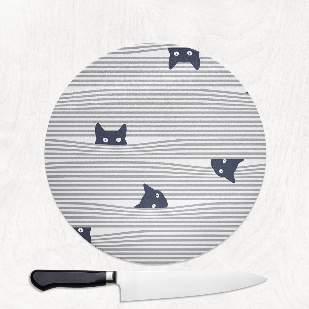 Round cutting board with cat pattern on a white surface with a knife.
