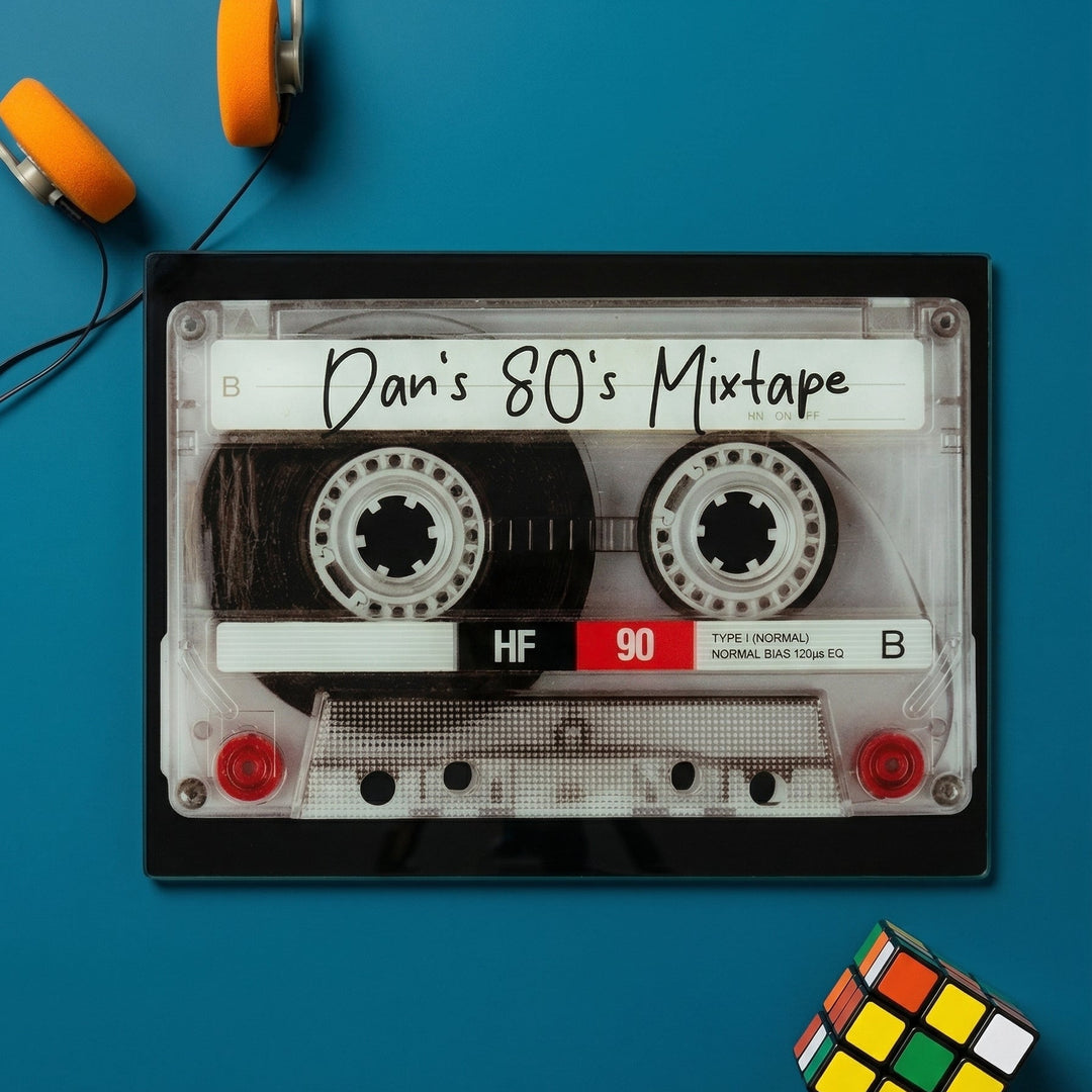 Personlaised Glass chopping board that looks like a Cassette tape labeled 'Dan's 80's Mixtape' on a dark green background with a rubix cube and headphones.