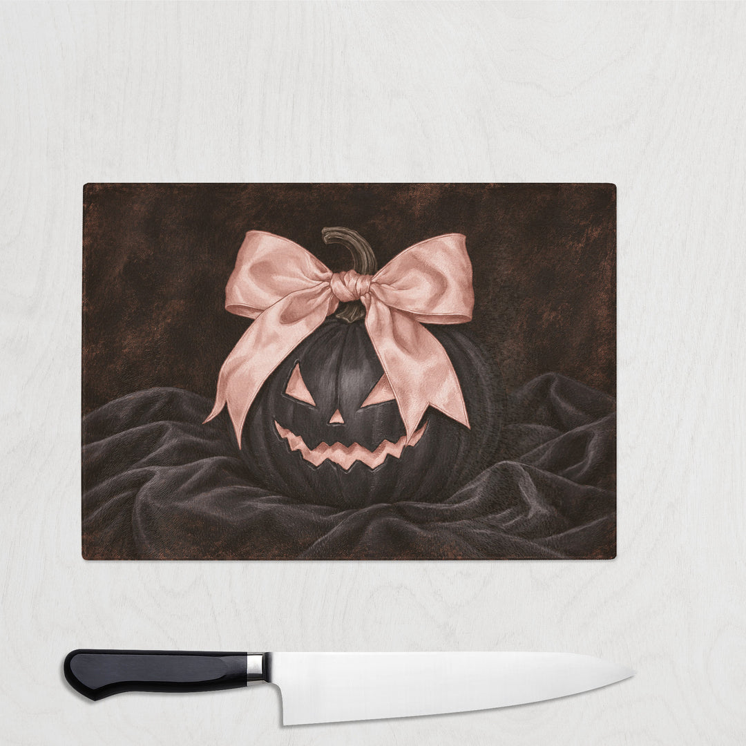 Pink Bow Black Pumpkin glass chopping board with a grinning black jack-o-lantern wearing a big pink satin bow