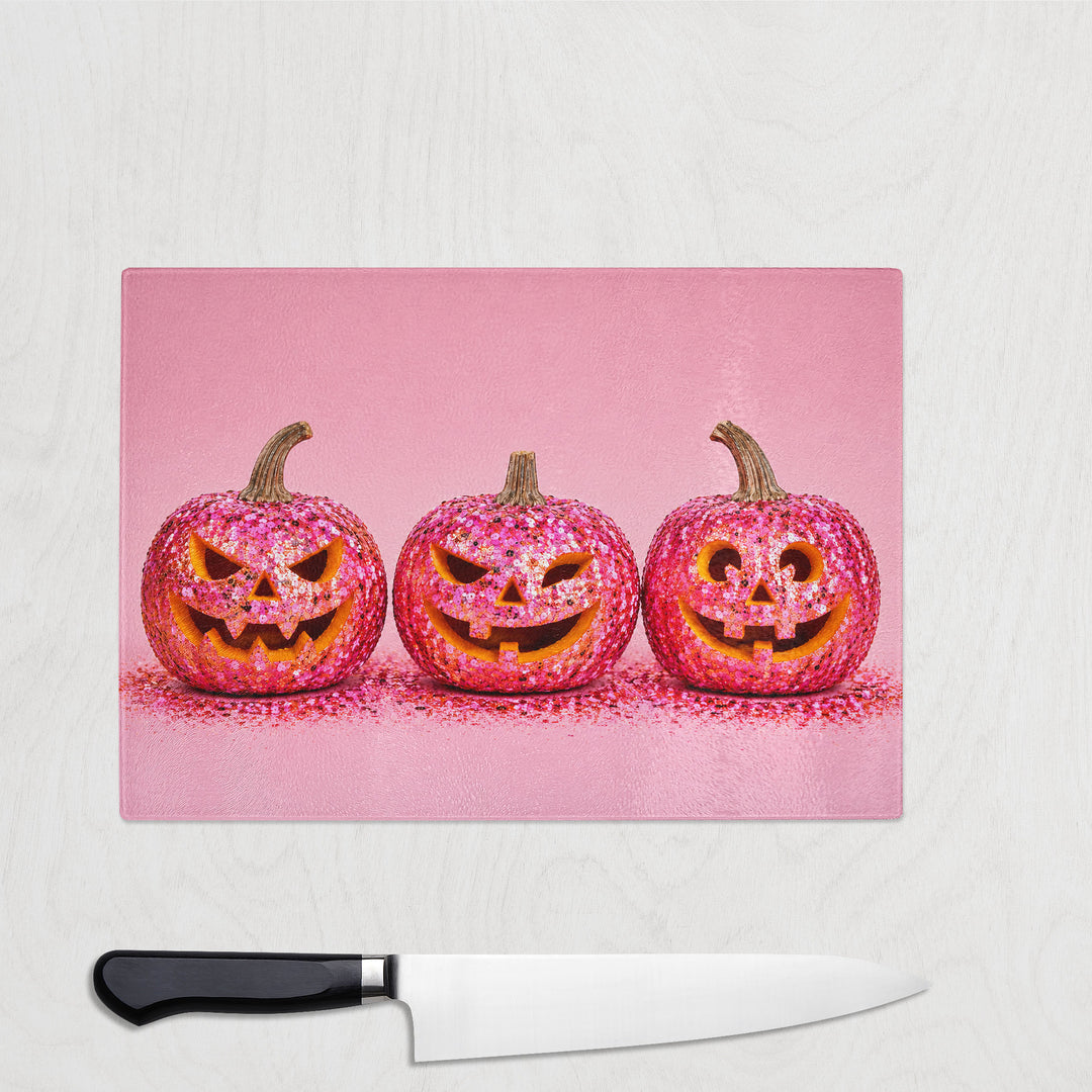 Pink Glitter Pumpkin glass chopping board with three hot pink sequin pumpkins grinning on soft pink