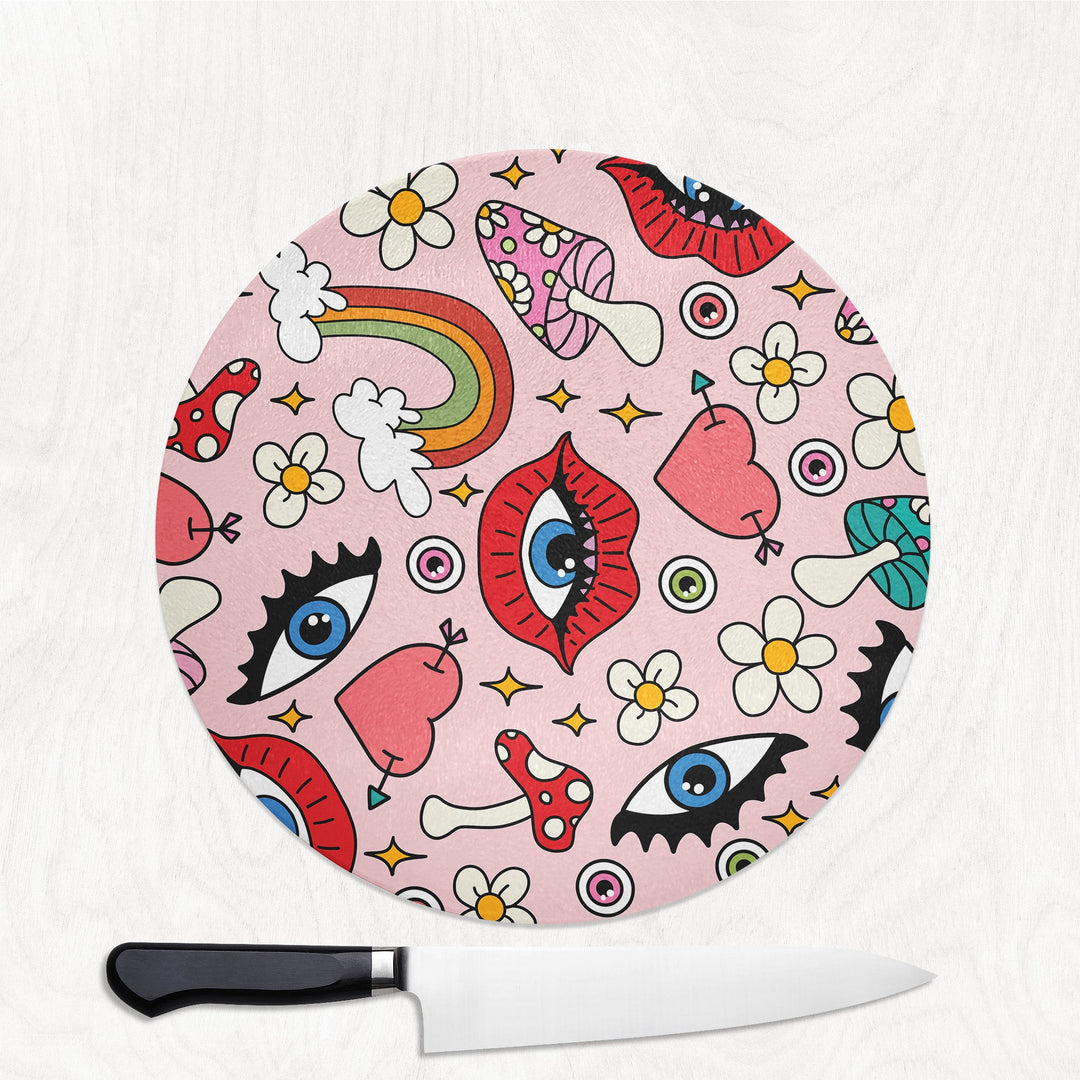 Round pink cutting board with colorful designs and a knife on a white background