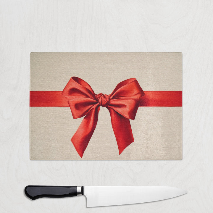 red bow glass chopping board on a white background with a knife underneath